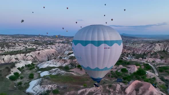 Hot air balloons fly over the mountainous landscape of Cappadocia, Turkey.