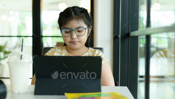Asian girl wearing glasses looking at tablet to study online. / Photodune, Misc