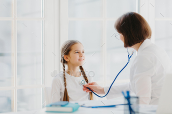 Small girl listens consult of professional experienced doctor who listens her lungs with stethoscope / Photodune, Misc