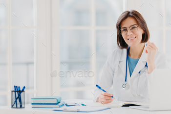 Woman intern works in hospital, writes in medical certificate, prescribes treatment for patient / Photodune, Misc