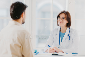 Professional woman doctor speaks with male patient, gives consultancy and makes prescription / Photodune, Misc