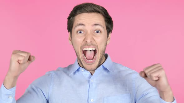 Young Man Celebrating Success on Pink Background