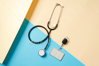 Overhead view of a stethoscope with a badge lying on a beige and blue background / Photodune, Misc