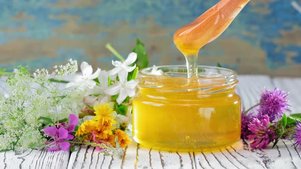 Honey in Glass Jar with Honey Dipper Over Rustic Wooden Background