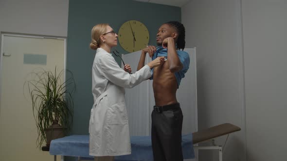 Female Doctor Examining Young Male Patient Using Stethoscope Indoors