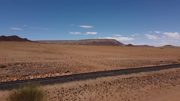 Colorful aerial view on the Namib desert with a railroad across it, blue sky