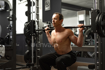 Senior man working out at the gym doing squats / Photodune, Misc