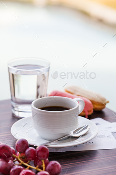 White mug with black coffee with eclairs and a glass of drinking water. / Photodune, Misc