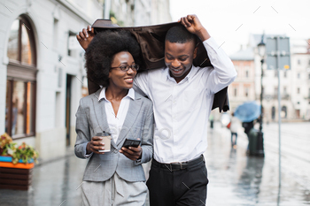 Afro man and woman hiding from rain under jacket / Photodune, Misc