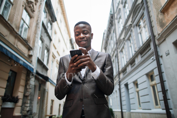 African man in suit standing on street with smartphone / Photodune, Misc