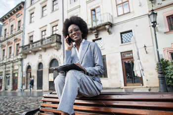 Smiling african woman having mobile conversation outdoors / Photodune, Misc