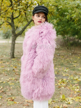 air and makeup posing in pink lama fur coat at the park. City fashion. Trendy girl