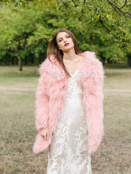 air and makeup posing in pink lama fur coat at the park. City fashion. Trendy girl
