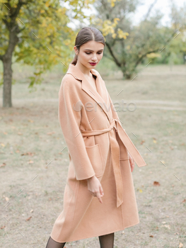 公園を歩いている長いトレンチコートの茶色の髪の女性。 / Photodune, Misc