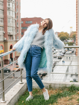 air and makeup posing in blue lama fur coat at rooftop. City fashion. Trendy girl
