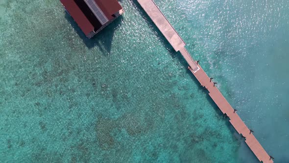 Aerial flyover beautiful Azure Blue Water, Ocean Waves Crashing On Wild Beach and footbridge.