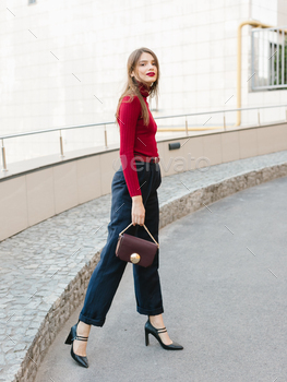 Stylish woman wearing red dress and blue shirt, black purse, walking on the street. / Photodune, Misc