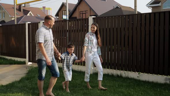 Father and Pretty Mother Hold Happy Little Boy Hands