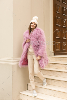 nd makeup posing in pink and blue lama fur coat at Milan street. City fashion. Trendy girls