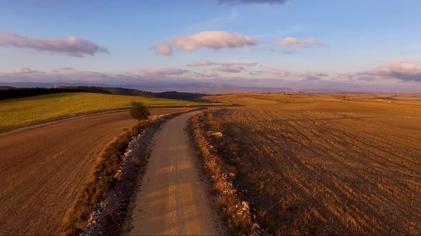 Aerial Bird View Footage Flight Over Rural Road in Beautiful Countryside Landscape at Sunset.