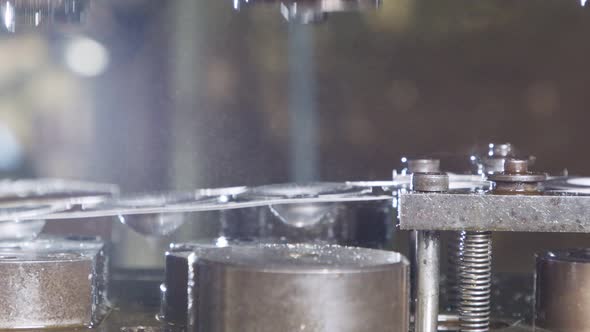 Close up of a punch press forming metal parts in a production line