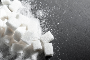 Sugar lumps piled up together against a black background / Photodune, Misc