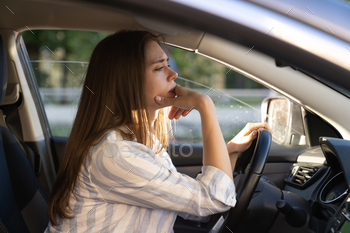 Sad tired young woman driving car. Unhappy girl driver depressed and anxious hold steering wheel / Photodune, Misc