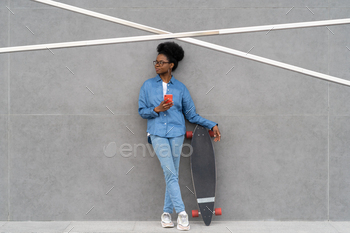 Stylish african girl with smartphone hold longboard. Trendy casual young woman chat in mobile phone / Photodune, Misc