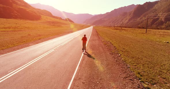 Low Altitude Flight in Front of Sporty Man at Perfect Asphalt Road