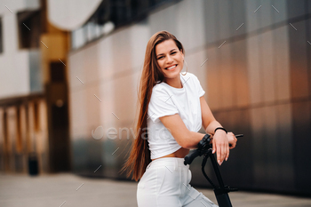 beautiful girl in white stylish clothes on an electric scooter in the city / Photodune, Misc