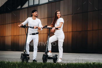 A girl and a guy are walking on electric scooters around the city, a couple in love on scooters / Photodune, Misc