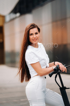beautiful girl in white stylish clothes on an electric scooter in the city / Photodune, Misc