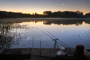 At night, two fishing rods are installed on the pier for fishing on the lake / Photodune, Misc