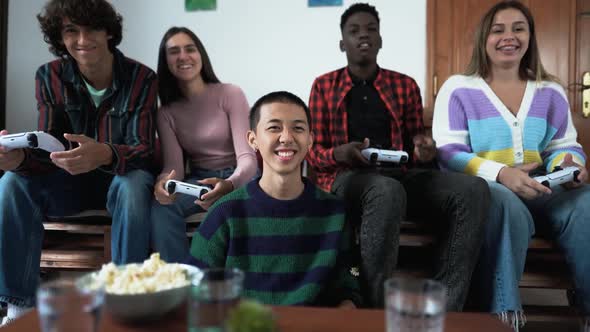 Young multiracial teenagers playing online video game console at home