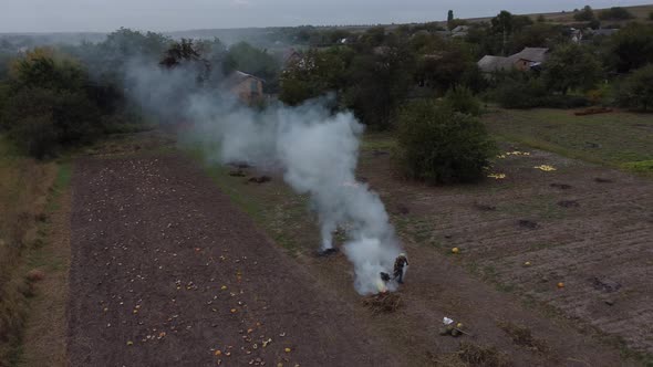 a woman works hard in harmful smoke in a vegetable garden in a village in Ukrain