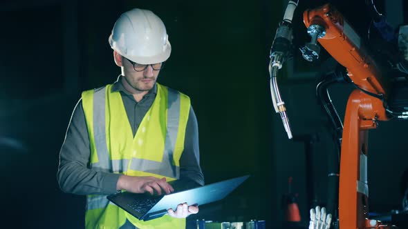 Male Engineer Is Managing a Robotic Device with the Laptop