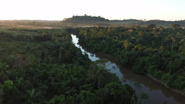 Drone Flies Over A River, In The Middle Of The Amazon Rainforest, While Clouds Appear On The Horizon