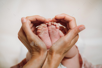 the feet of the newborn in the hands of the mother holds in the form of a heart. children's feet / Photodune, Misc