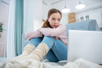 Teen girl sitting on the floor looking at laptop screen. / Photodune, Misc