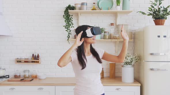 Young Woman in VR Glasses in Kitchen at Home