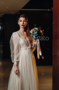 Stylish red-haired bride in a dress with sleeves and a bouquet in the interior / Photodune, Misc