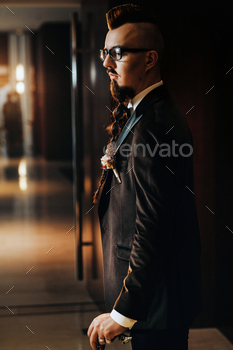 The groom in a tuxedo and bow tie with a mohawk hairstyle and a cane in the interior / Photodune, Misc