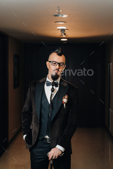 The groom in a tuxedo and bow tie with a mohawk hairstyle and a cane in the interior / Photodune, Misc