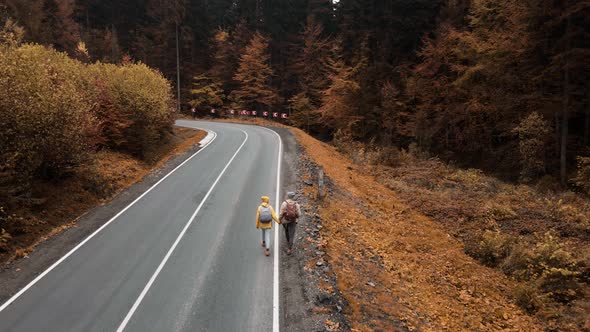 Aerial Top View Couple Hikers Travelers Walking Along Winding Empty Asphalt Road on Pictorial Hill