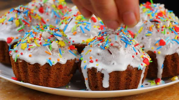 Woman Decorates Small Easter Cupcakes with White Frosting Pours Sweet Decor Nonparelle on Them