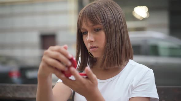 Beautiful Anxious Teenage Girl Looking at Hand Mirror Sitting on City Street Waiting for Boyfriend