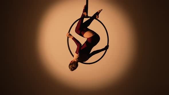 A Pretty Aerialist is Spinning Upside Down on an Aerial Ring High Under the Dome of the Circus