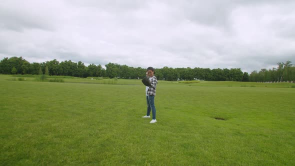 Happy School Age Black Boy in Baseball Glove Pitching on Green Field