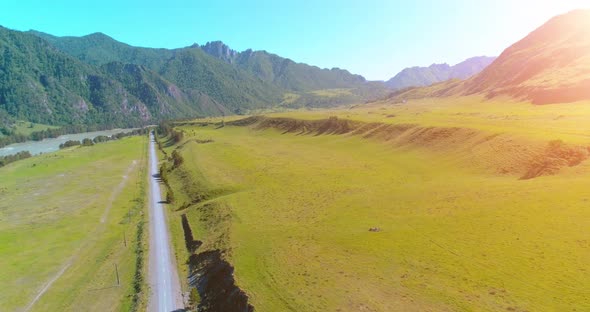 Aerial Rural Mountain Road and Meadow at Sunny Summer Morning. Asphalt Highway and River.