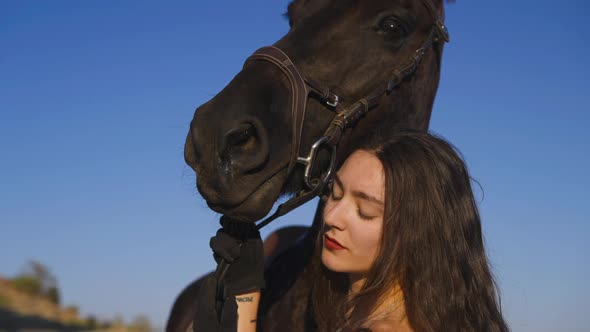 Side View of Gorgeous Young Woman Hugging Purebred Horse with Clear Blue Sky at Background